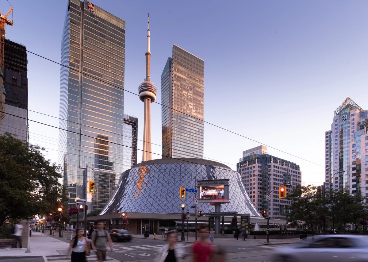 The CN Tower and Roy Thomson Hall among city skyscrapers at dusk.