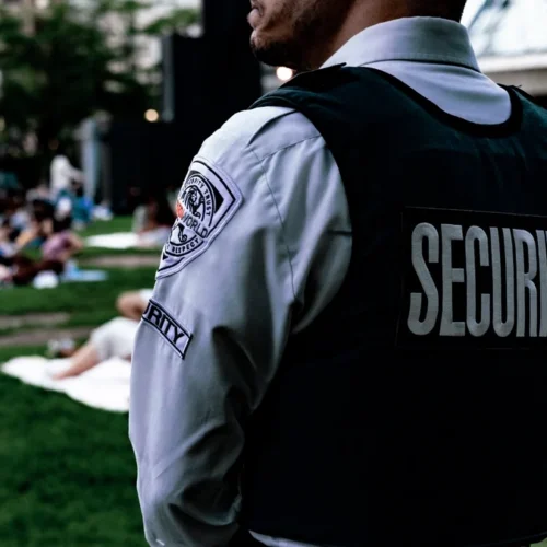 A security guard in a uniform standing at an outdoor event.