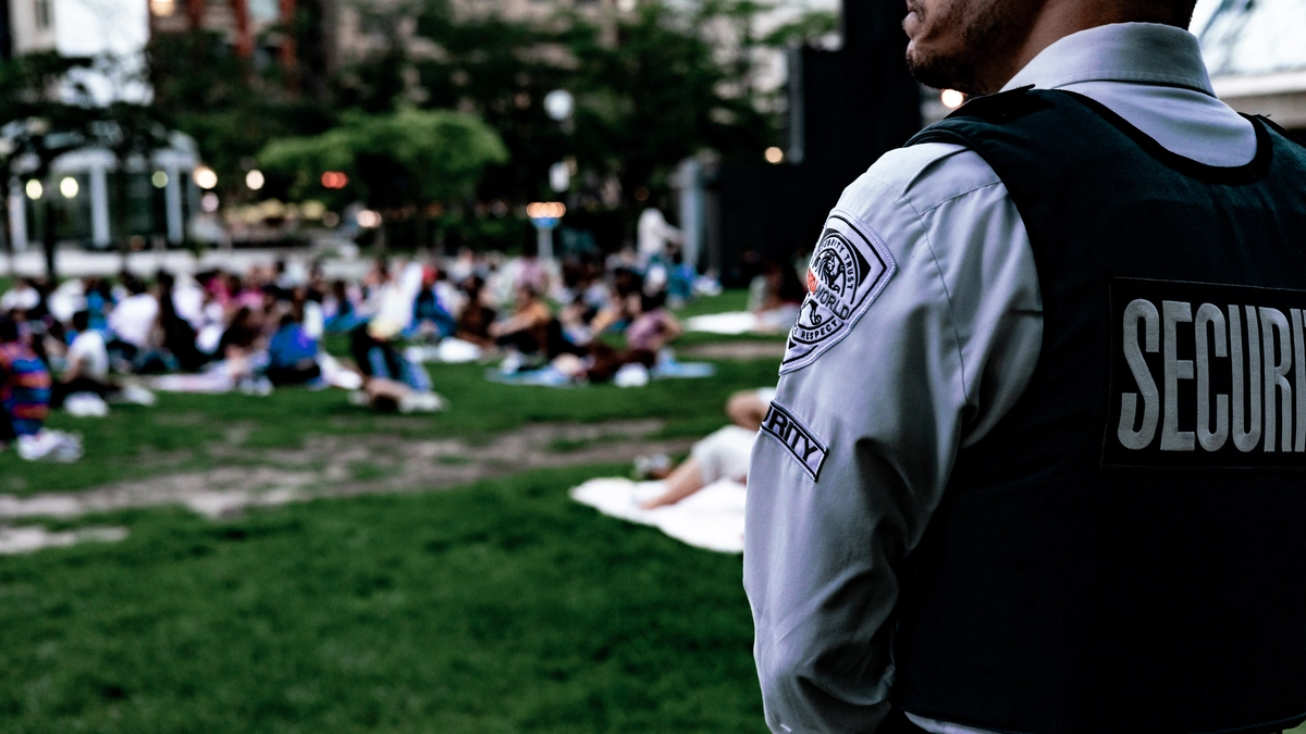 A security guard in a uniform standing at an outdoor event.