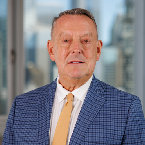 A middle-aged man wearing a blue plaid blazer, white shirt, and yellow tie.