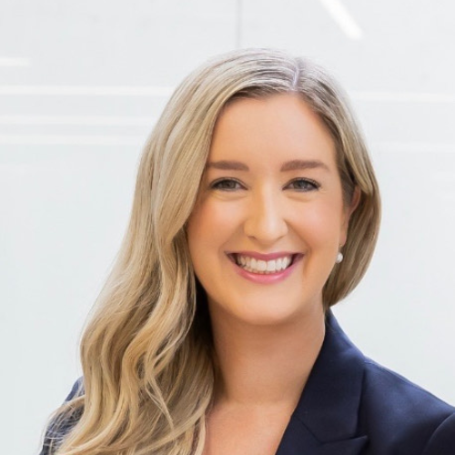 Headshot of a smiling woman with long blonde hair wearing a dark blazer.