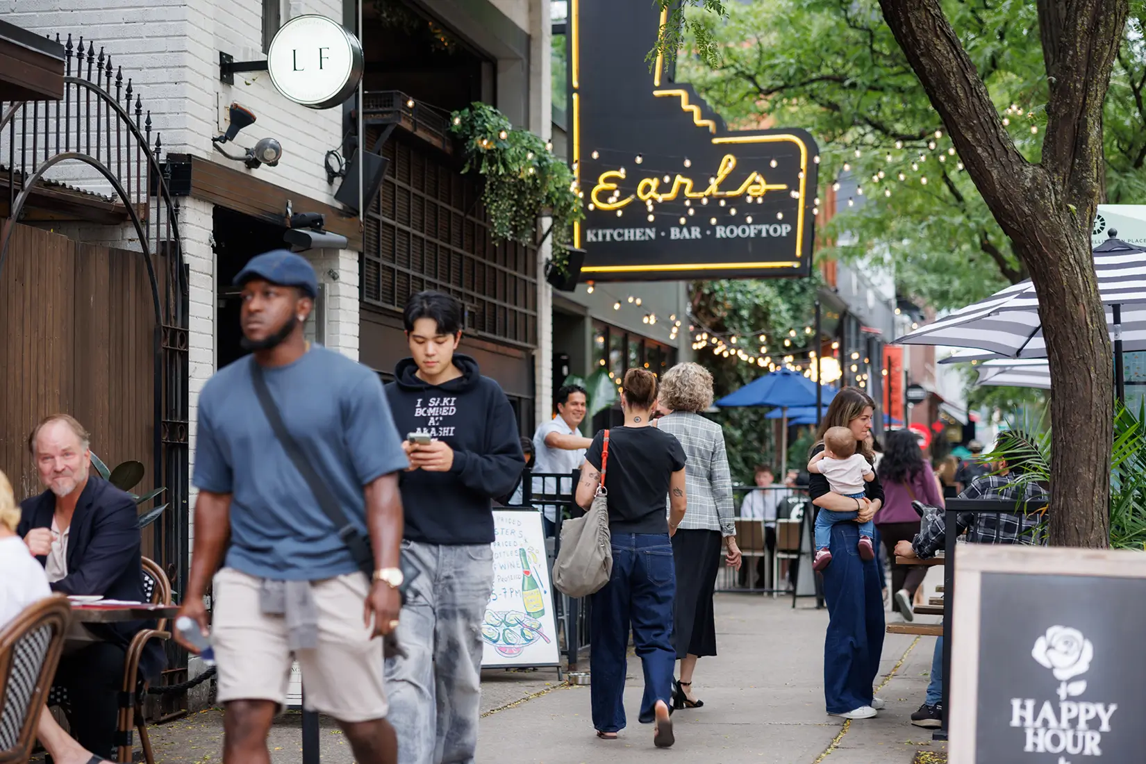 People walking on a sidewalk past the storefront of Earls Kitchen + Bar.