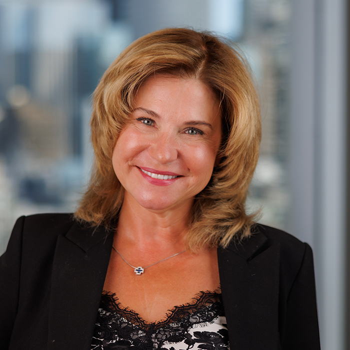 A smiling woman in a black blazer and lace-trimmed top.
