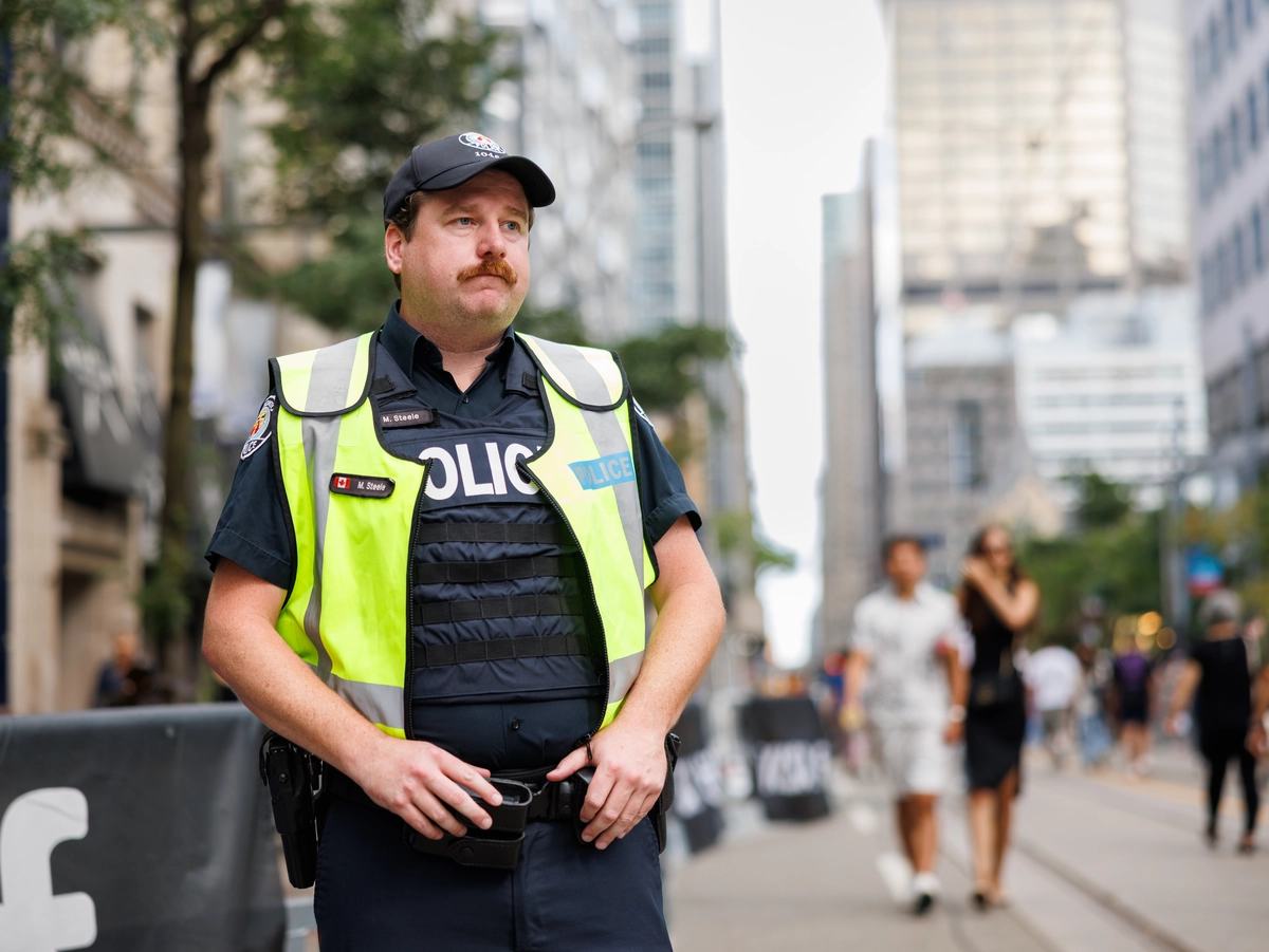 A police officer in a high-visibility vest stands on a city street.
