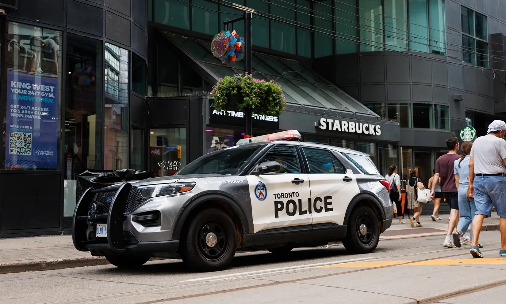 A Toronto Police cruiser parked on a city street in front of a Starbucks.