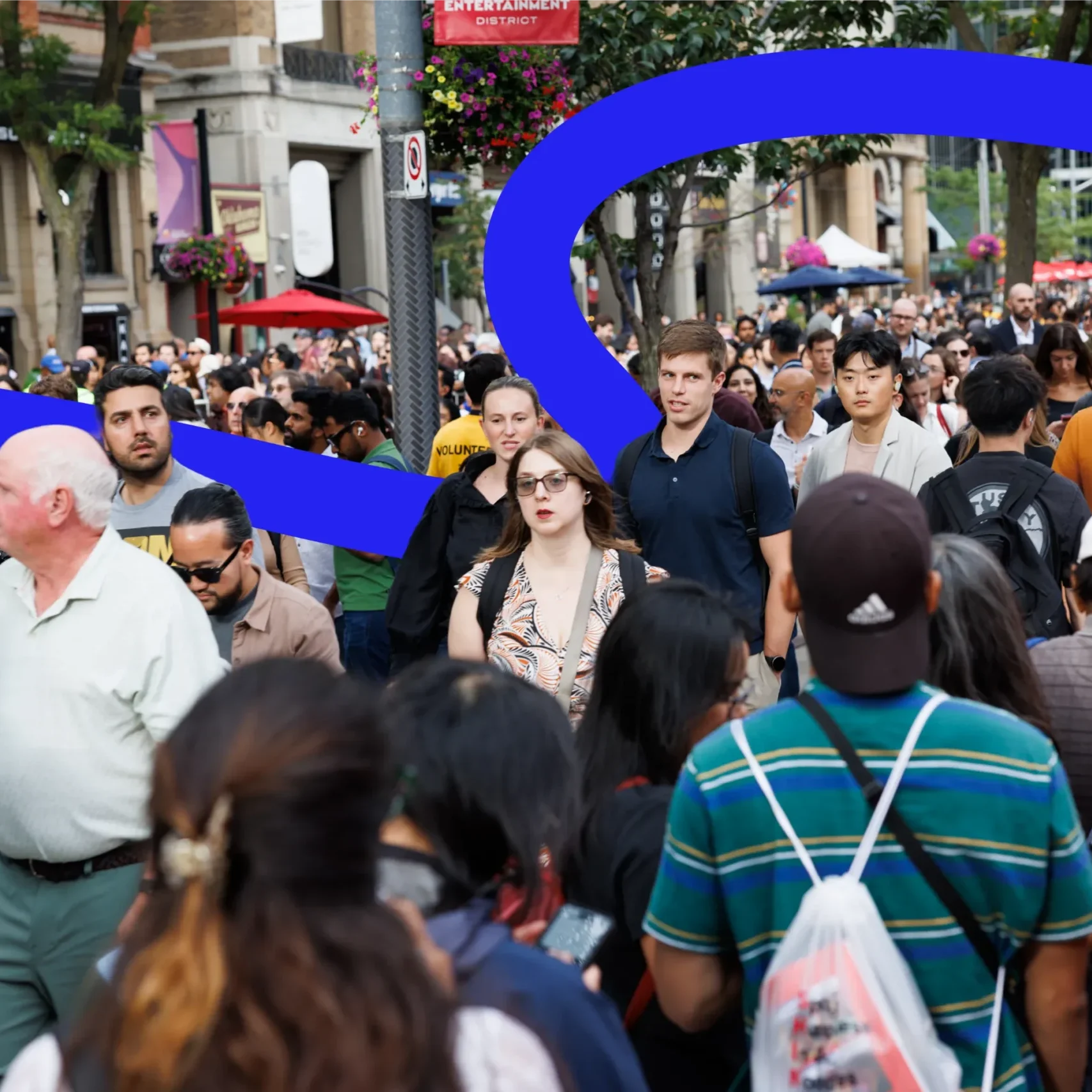A dense crowd of people walking down a city street in the Entertainment District.